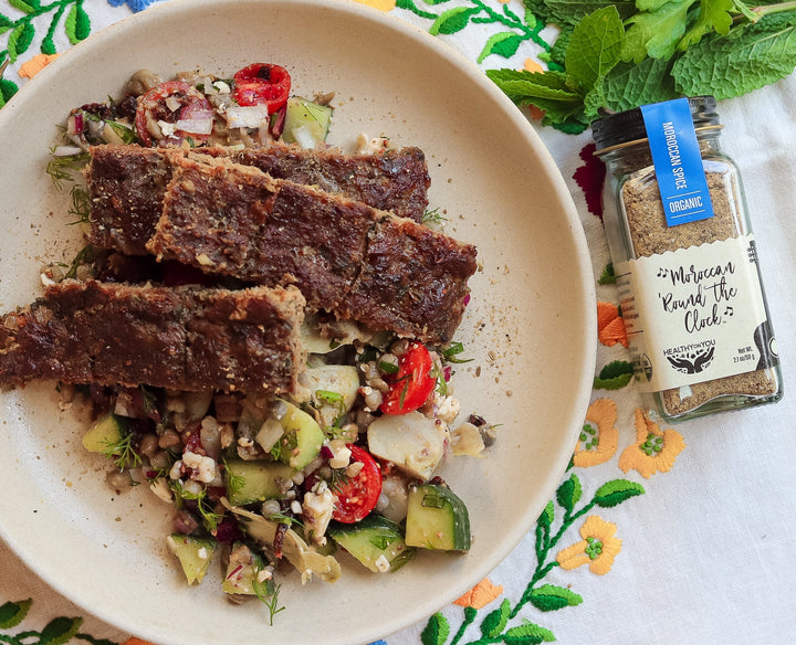 Sliced Moroccan beef kofta on a lentil cucumber salad, styled with a jar of Healthy On You Moroccan spice blend.