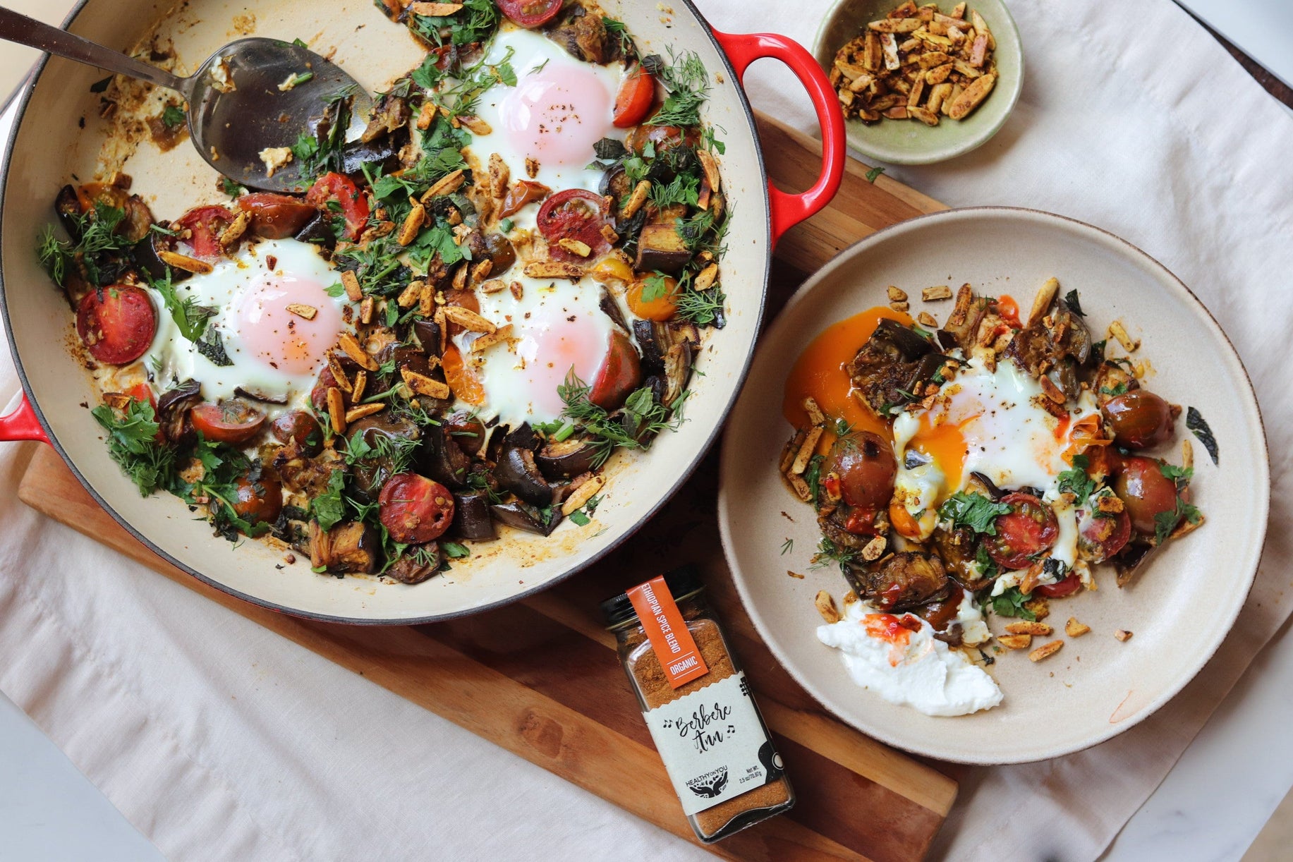 Fried eggs with vegetables and a side dish on a wooden board.